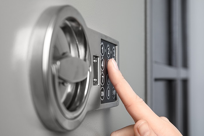 Woman opening steel safe with electronic lock, closeup