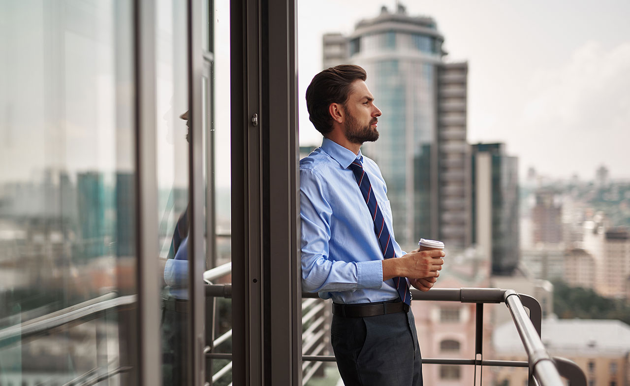 Personne en tenue professionnelle debout sur un balcon surplombant la ville