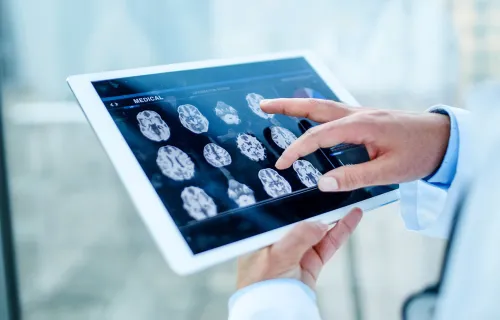 A doctor’s hand reviewing scan results from a mobile tablet