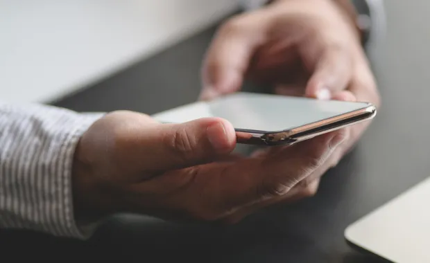 A woman uses smartphone to control utilities, representing CGI’s work with GRDF