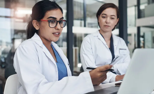 two medical professionals reviewing data at a monitor